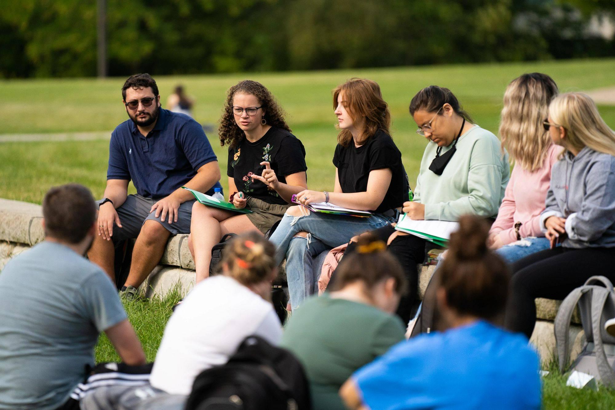 Students and a faculty member interact during an outdoor class session.